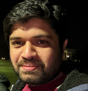 A man in a fuzzy hoodie looks at camera.