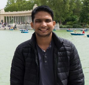 Ankush smiles for photo in front of large fountain monument with sailboats in water.