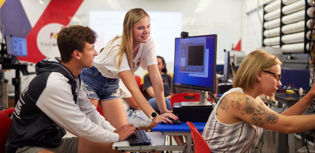 Three students work together inside a lab