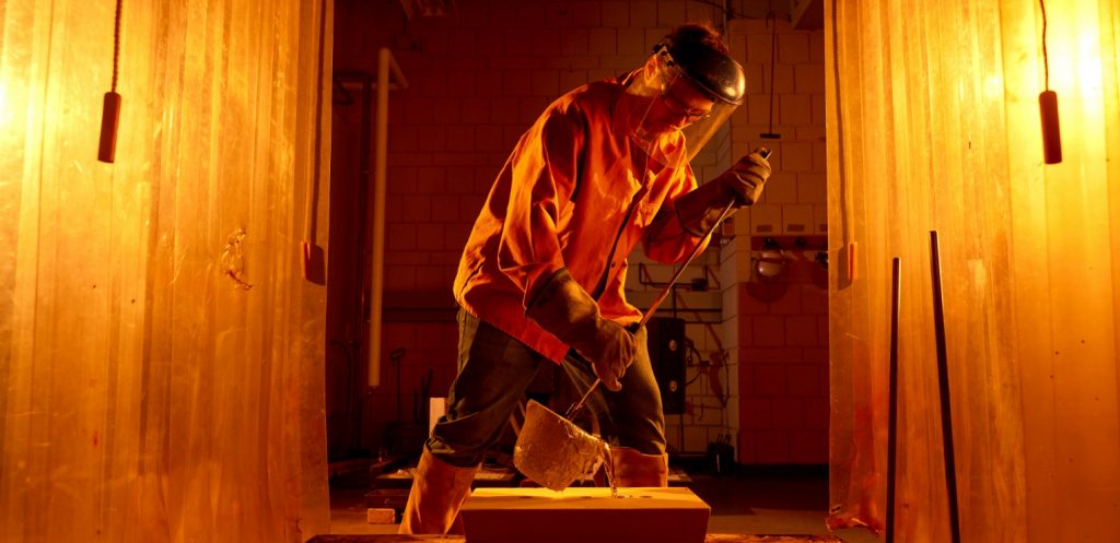 An instructor pours a cast of molten aluminum