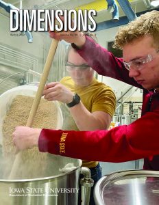 A cover of a magazine with a photo of two students working inside the beer brewing lab