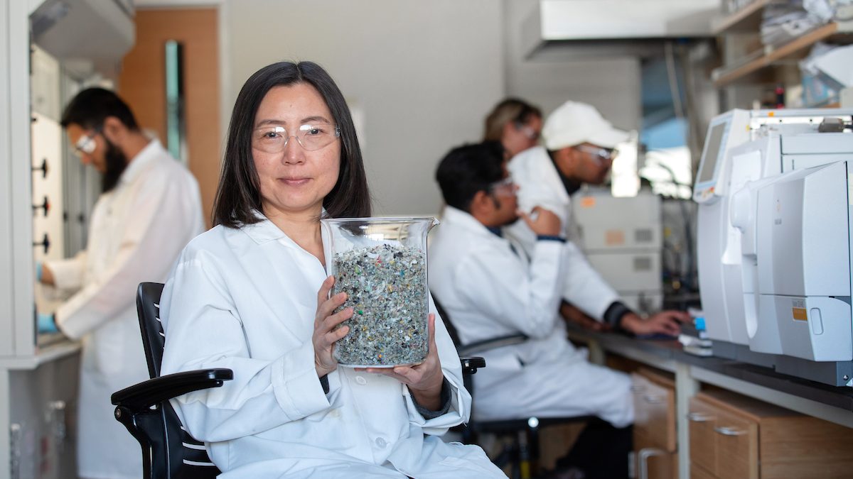 Xianglan Bai holds a beaker of shredded, single-use plastics