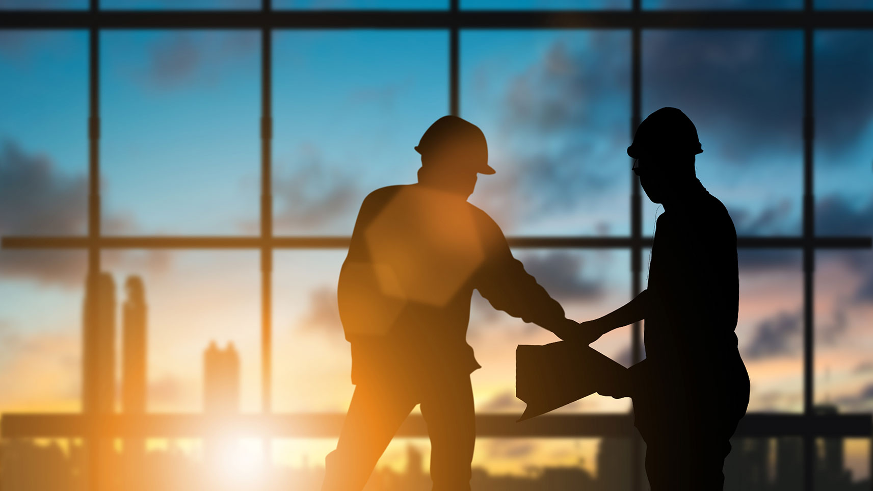 silhouette of workers reviewing building plans