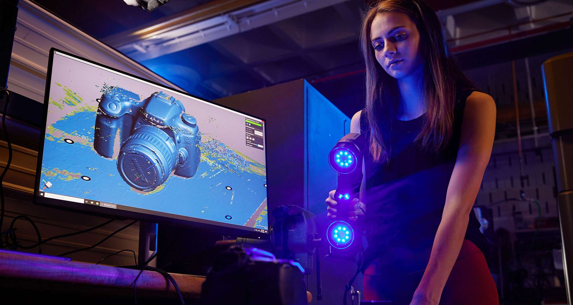 student using handheld 3D scanner to display object on desktop monitor